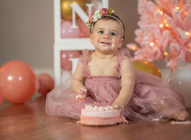 Baby girl smiles with cake on her face