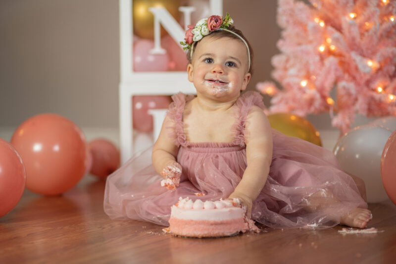 Baby girl smiles with cake on her face