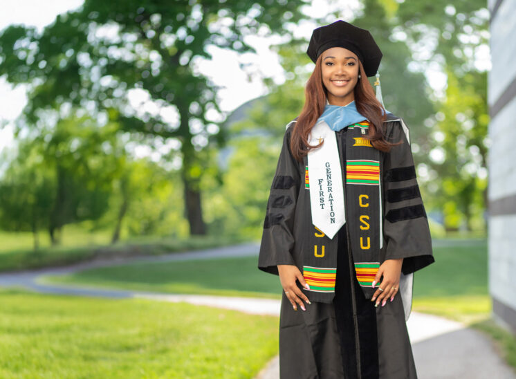 College graduate poses for photo on path