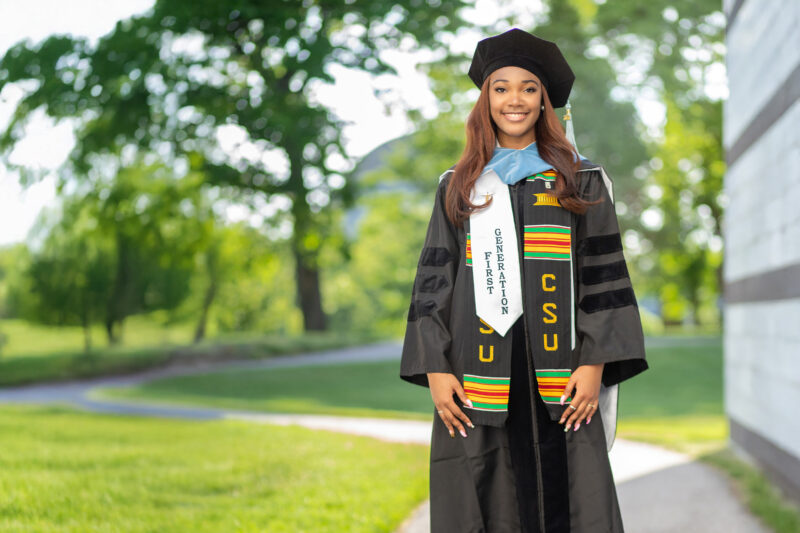 College graduate poses for photo on path