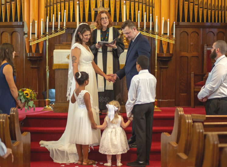Couple hold hands with kids at wedding