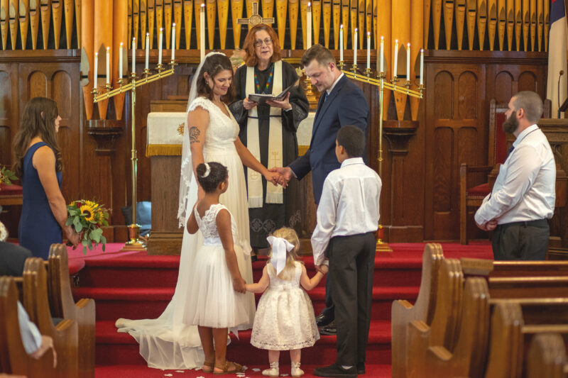 Couple hold hands with kids at wedding