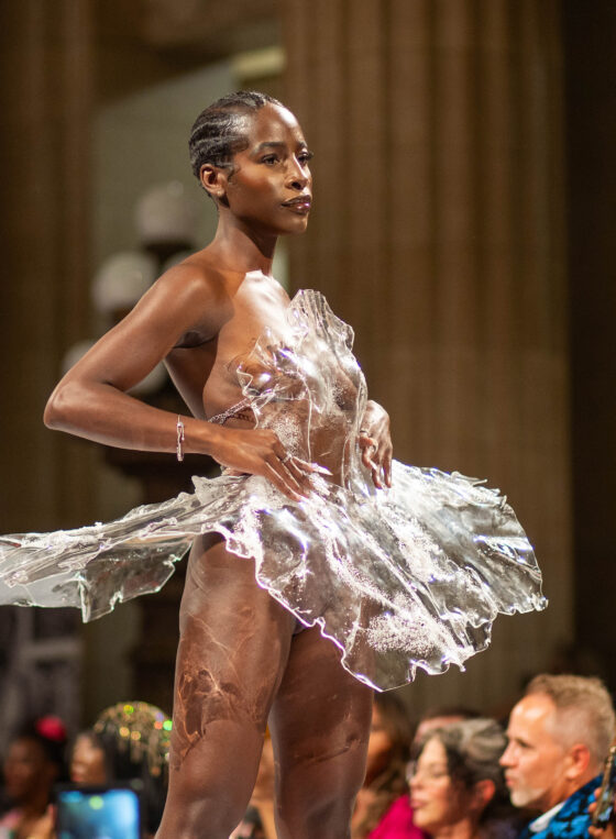 Model in plastic dress stands on runway in Cleveland