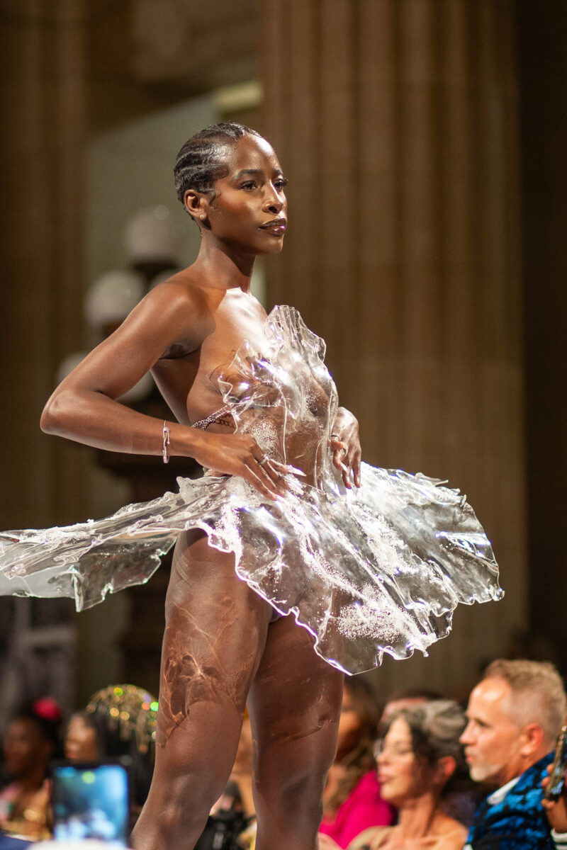 Model in plastic dress stands on runway in Cleveland