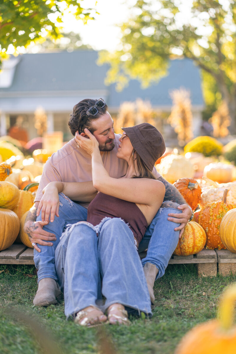 Engaged couple sit among pumpkins after surprise proposal